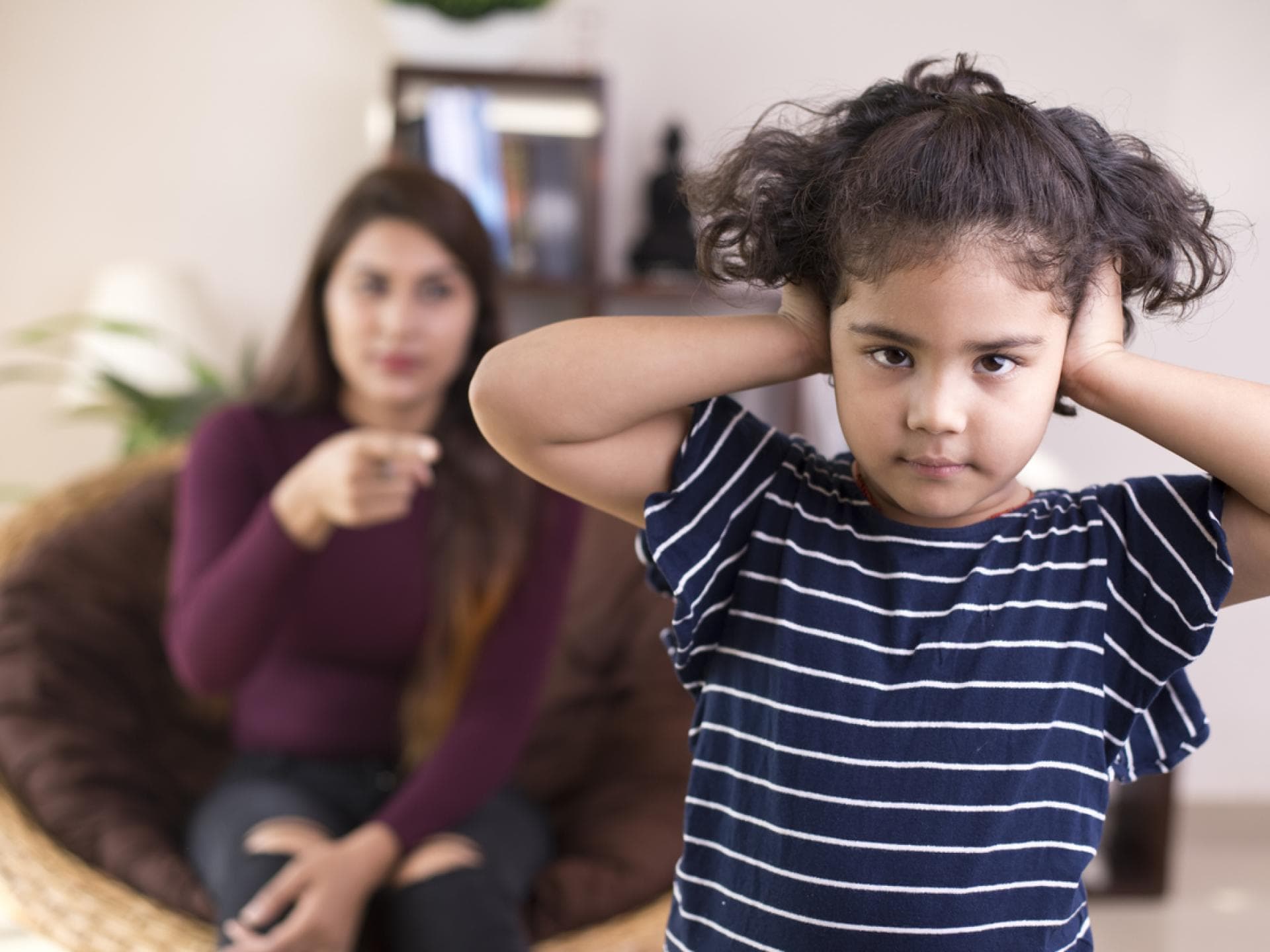 Toxische Sätze können bei Kindern tiefe Spuren hinterlassen. Mama schimpft, Mädchen hält sich die Ohren zu.