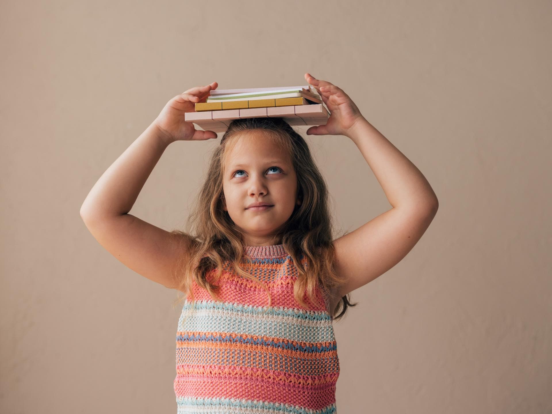 Ist es wirklich so wichtig, dass Kinder gerade stehen? Mädchen balanciert Bücher auf dem Kopf.