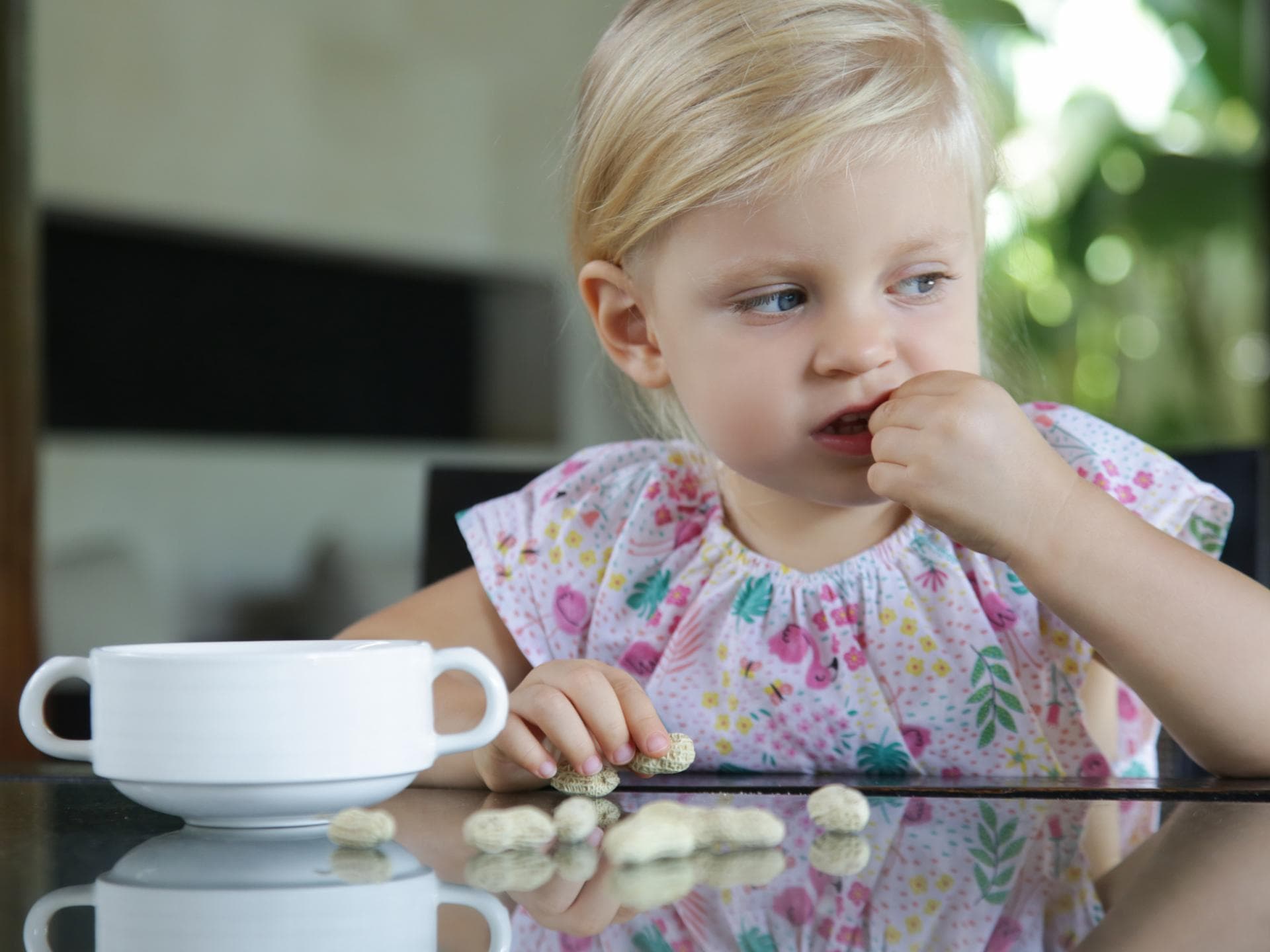 Viele Eltern fragen sich, ab wann Kinder Nüsse essen dürfen. Ein kleines Mädchen isst Erdnüsse.