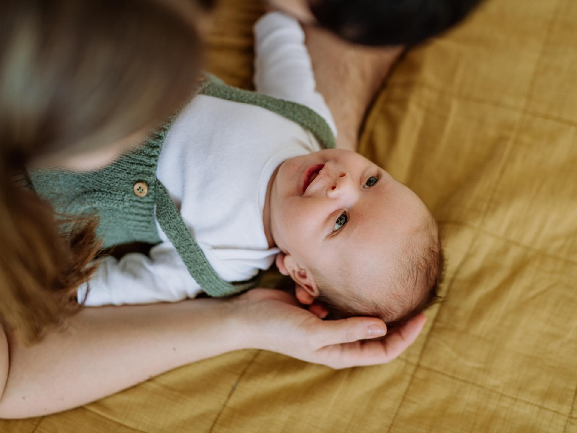 Die Babynamen der Stars gehen zurück zu klassisch. Eltern beugen sich über ihr Baby.