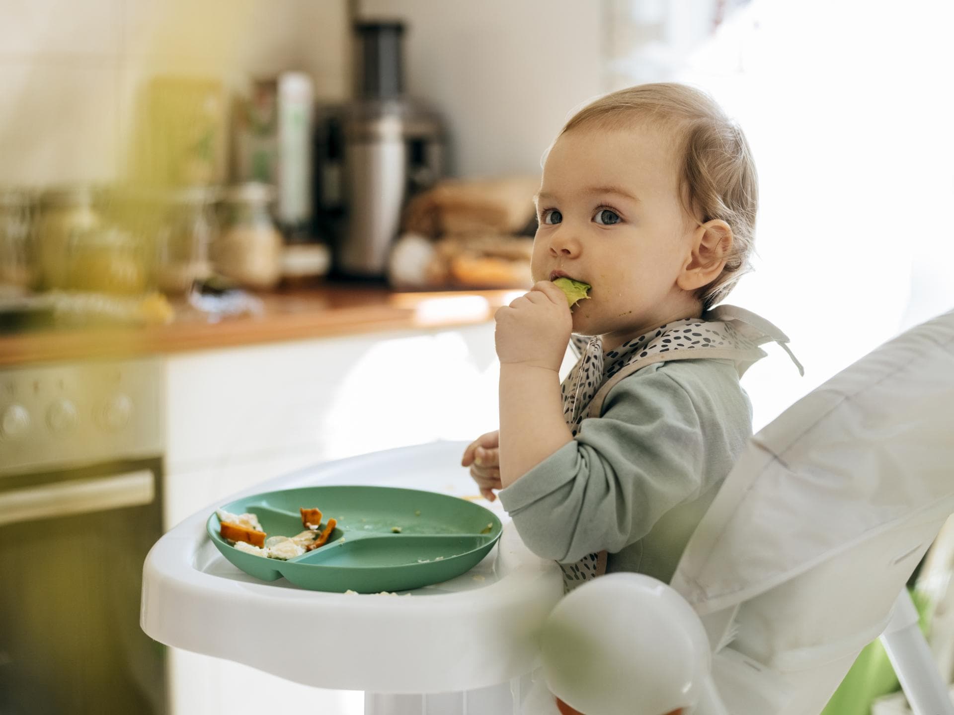 Müsliriegel für Babys wegen Schimmel zurückgerufen. Baby isst im Hochstuhl.