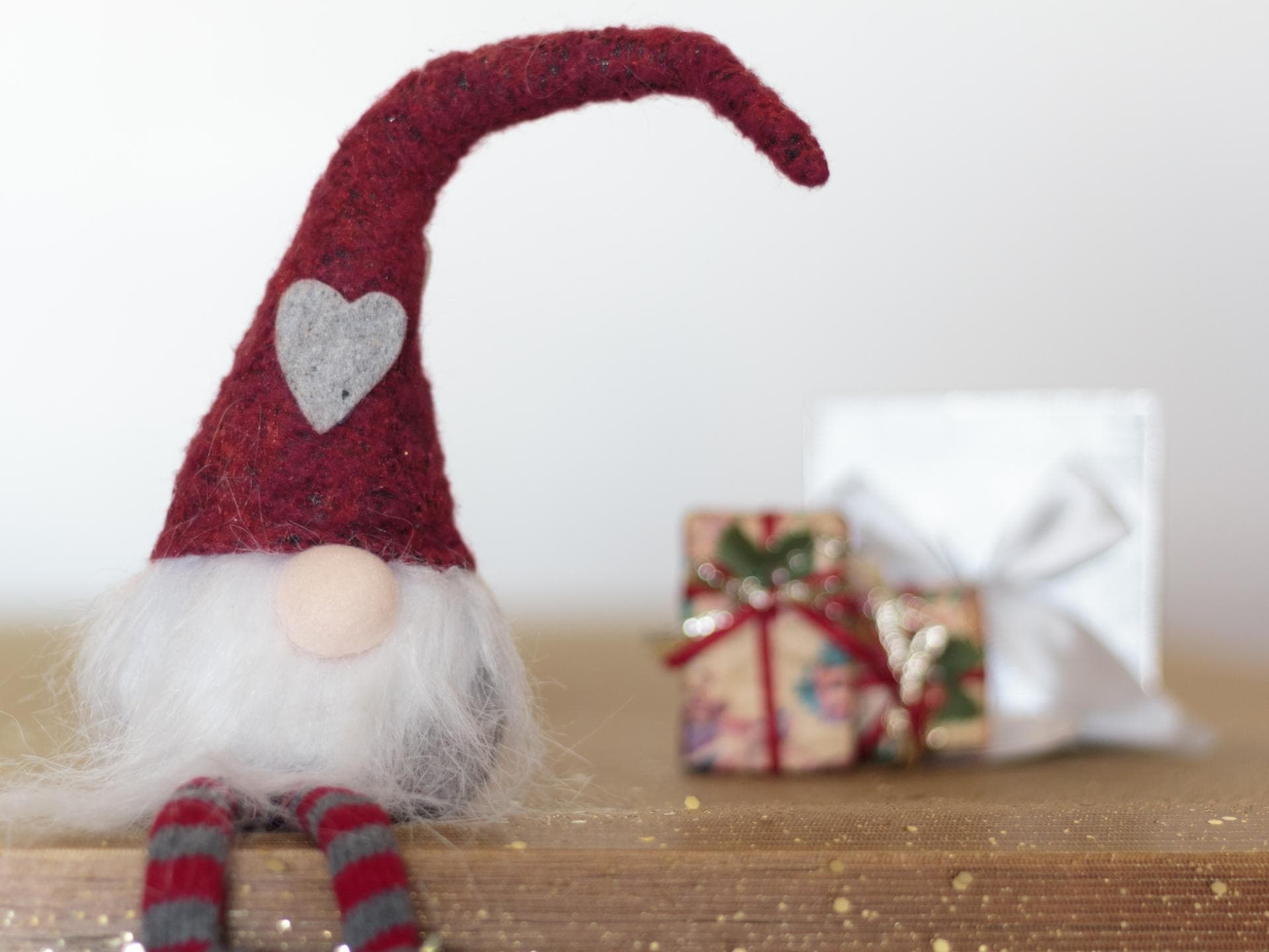 Der Wichtel zieht nach Weihnachten meist wieder aus. Wichtel sitzt vor Geschenken.