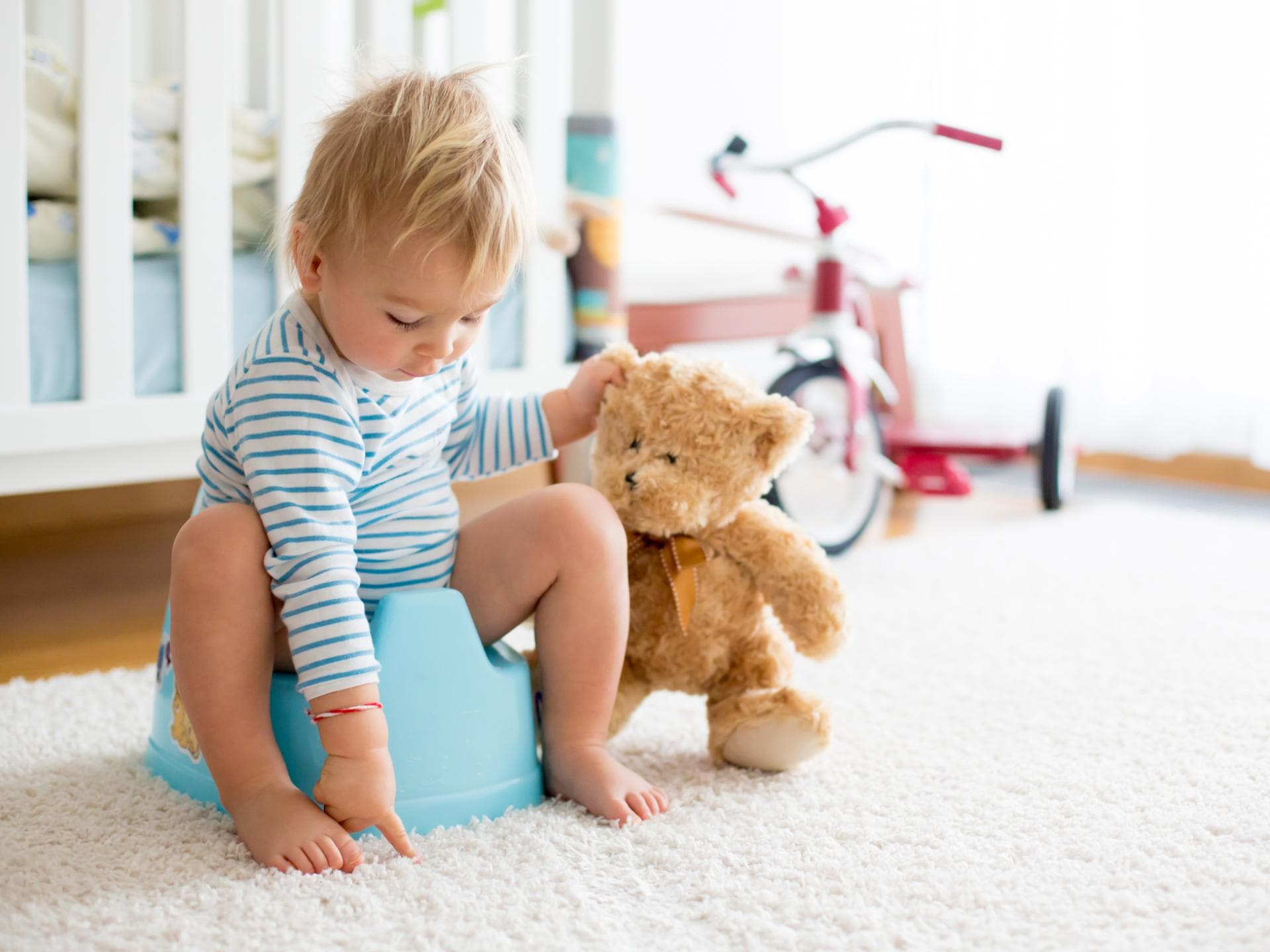 Wenn Kinder abends noch mal Pipi müssen, steckt oft das Bedürfnis nach Nähe dahinter. Kleinkind sitzt auf dem Töpfchen.