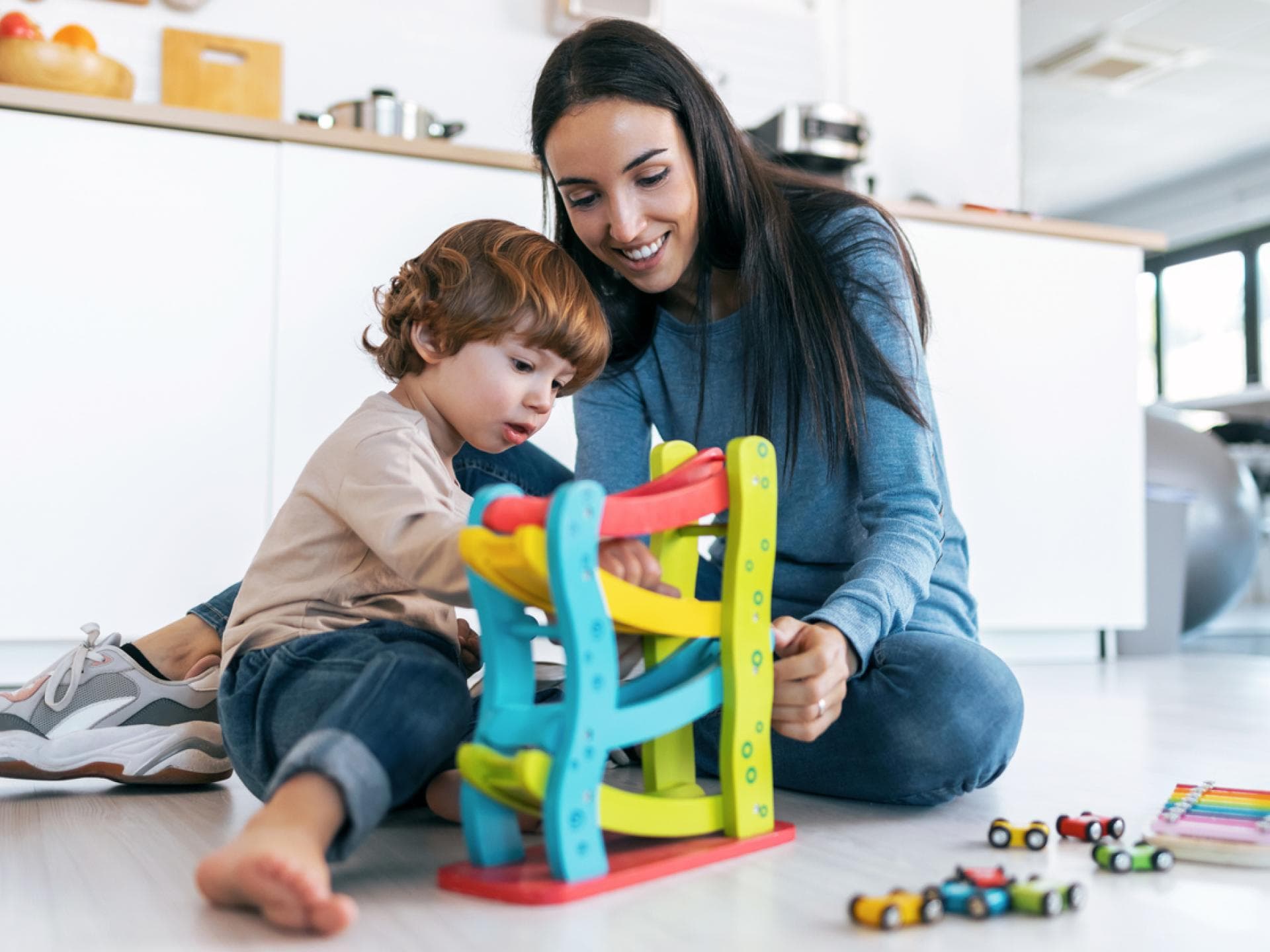 Gemeinsames Spiel stärkt die Eltern-Kind-Bindung. Mutter spielt auf dem Boden mit ihrem Sohn.