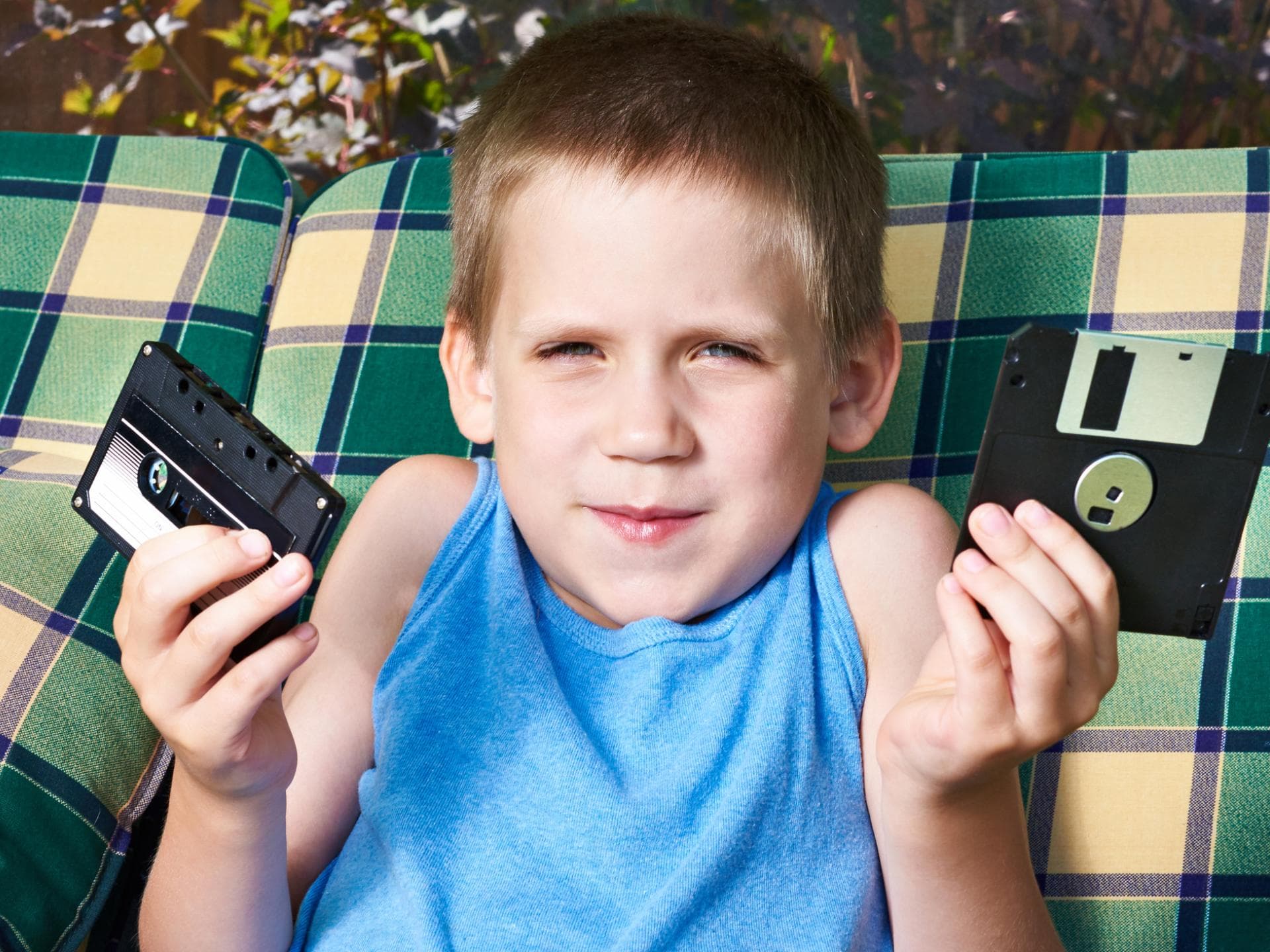 Wir zeigen euch typische Jungennamen der 80er-Jahre. Eine Junge hält eine Kassette und eine Disc in den Händen.