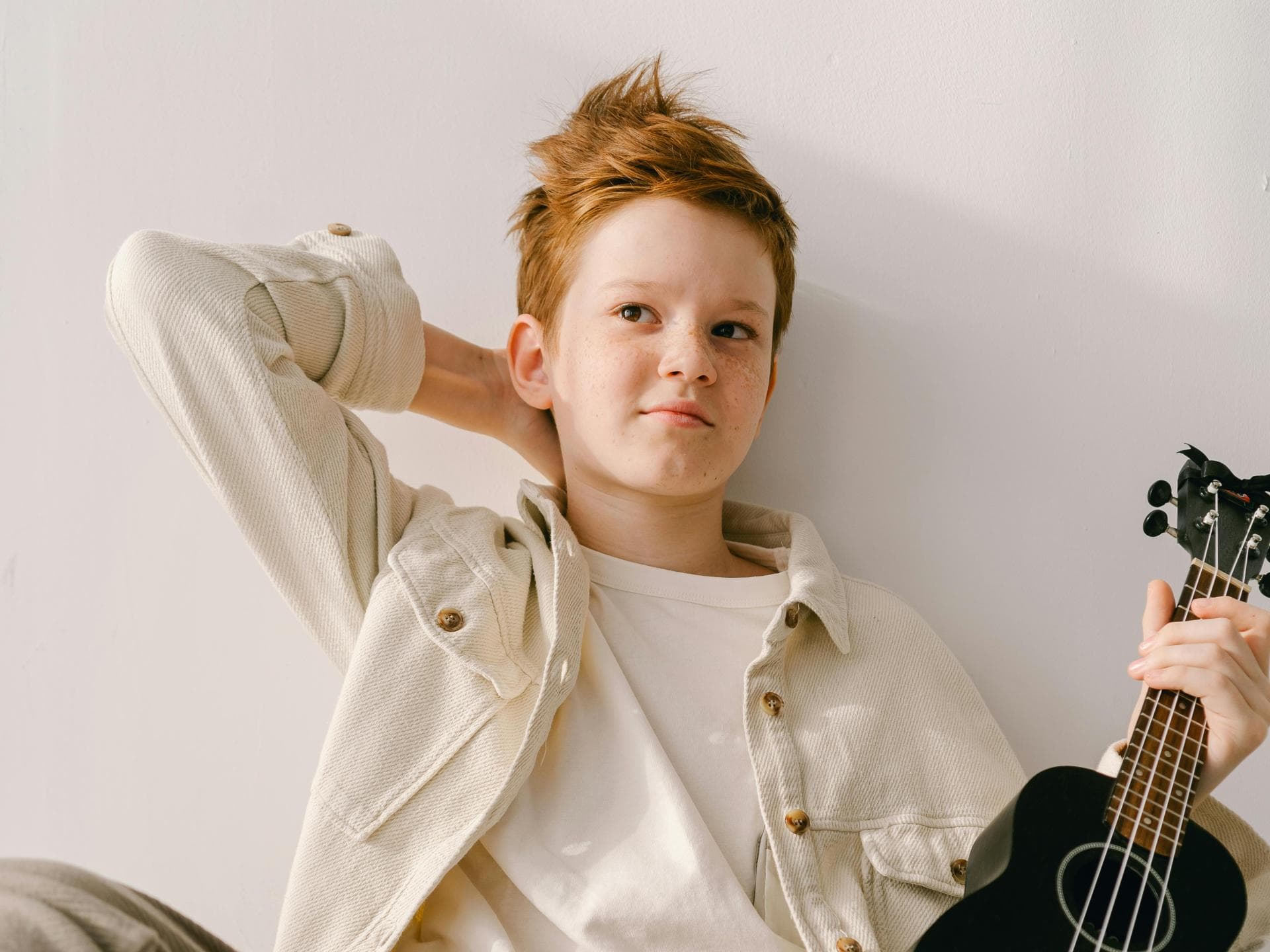 Lässig nach oben geföhnte Haare Ein Junge mit Gitarre