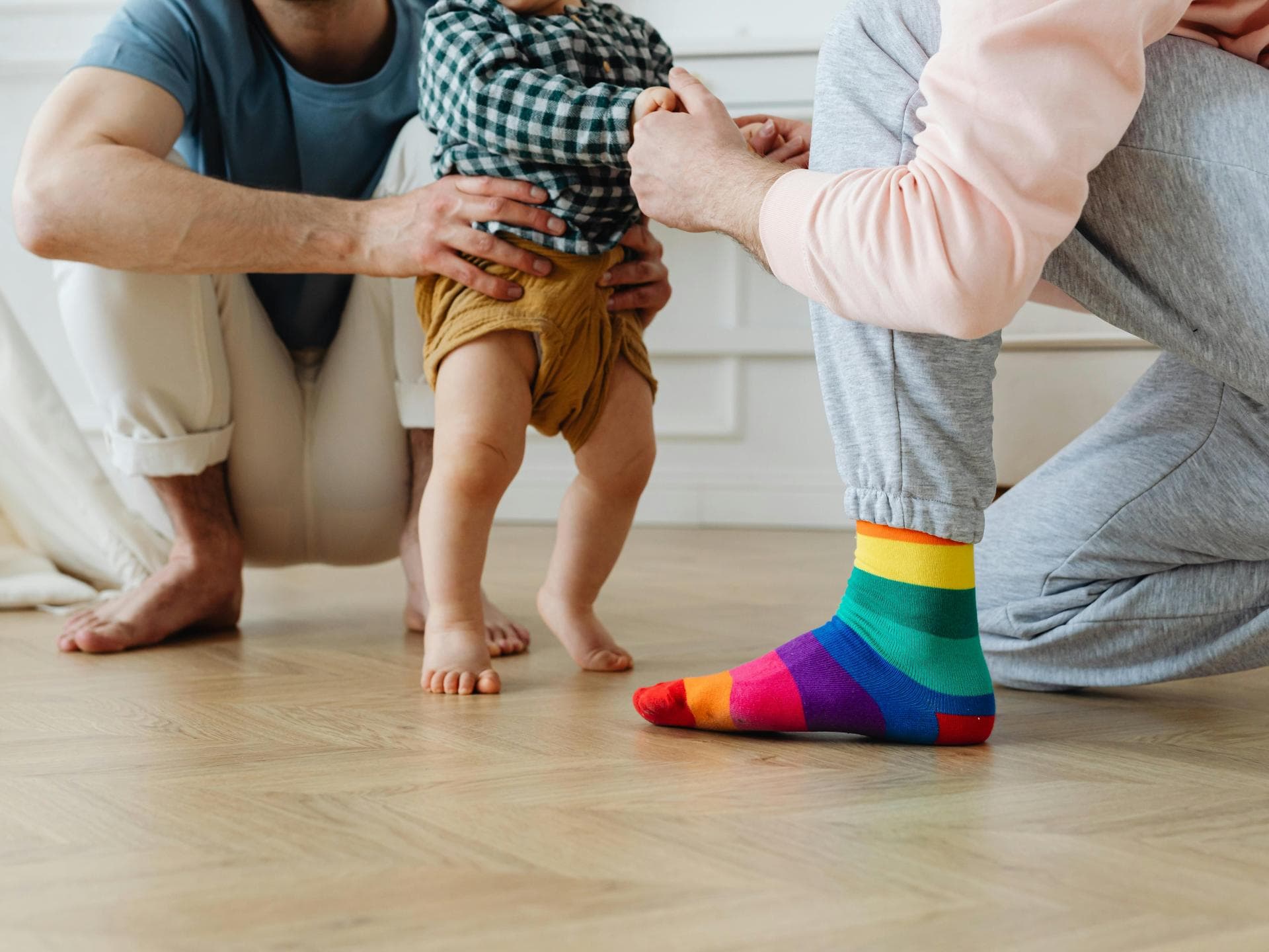 Barfuß ist am besten – vor allem zum Start. Baby läuft barfuß mit Hilfe von einem zum anderen.