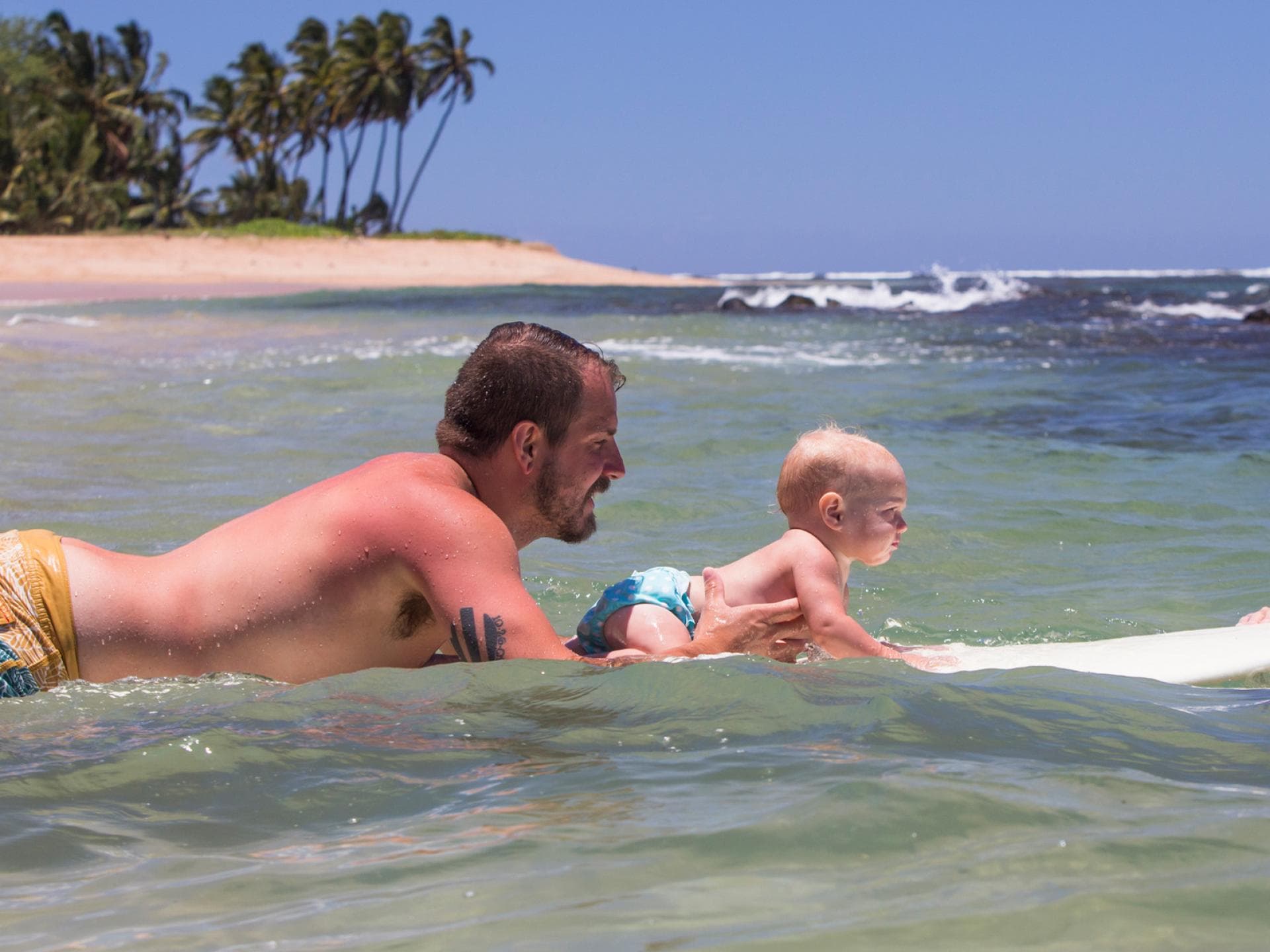 Der Papa hat bereits verbrannte Schultern – und das Baby vermutlich auch bald! UV-Kleidung würde beiden helfen ...