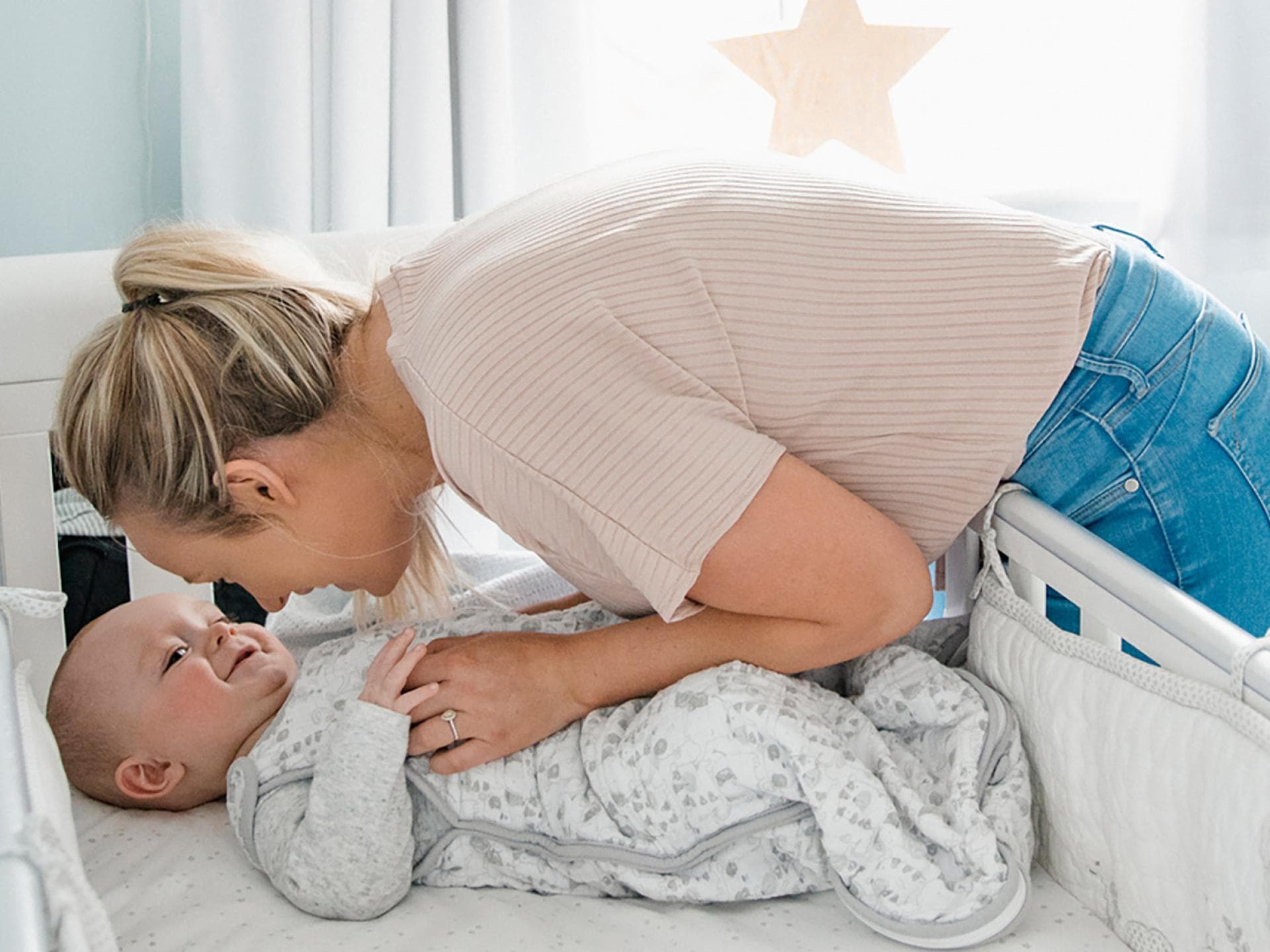 Schlaflieder haben zahlreiche positive Effekte. Eine Mama bringt ihr Baby ins Bett.
