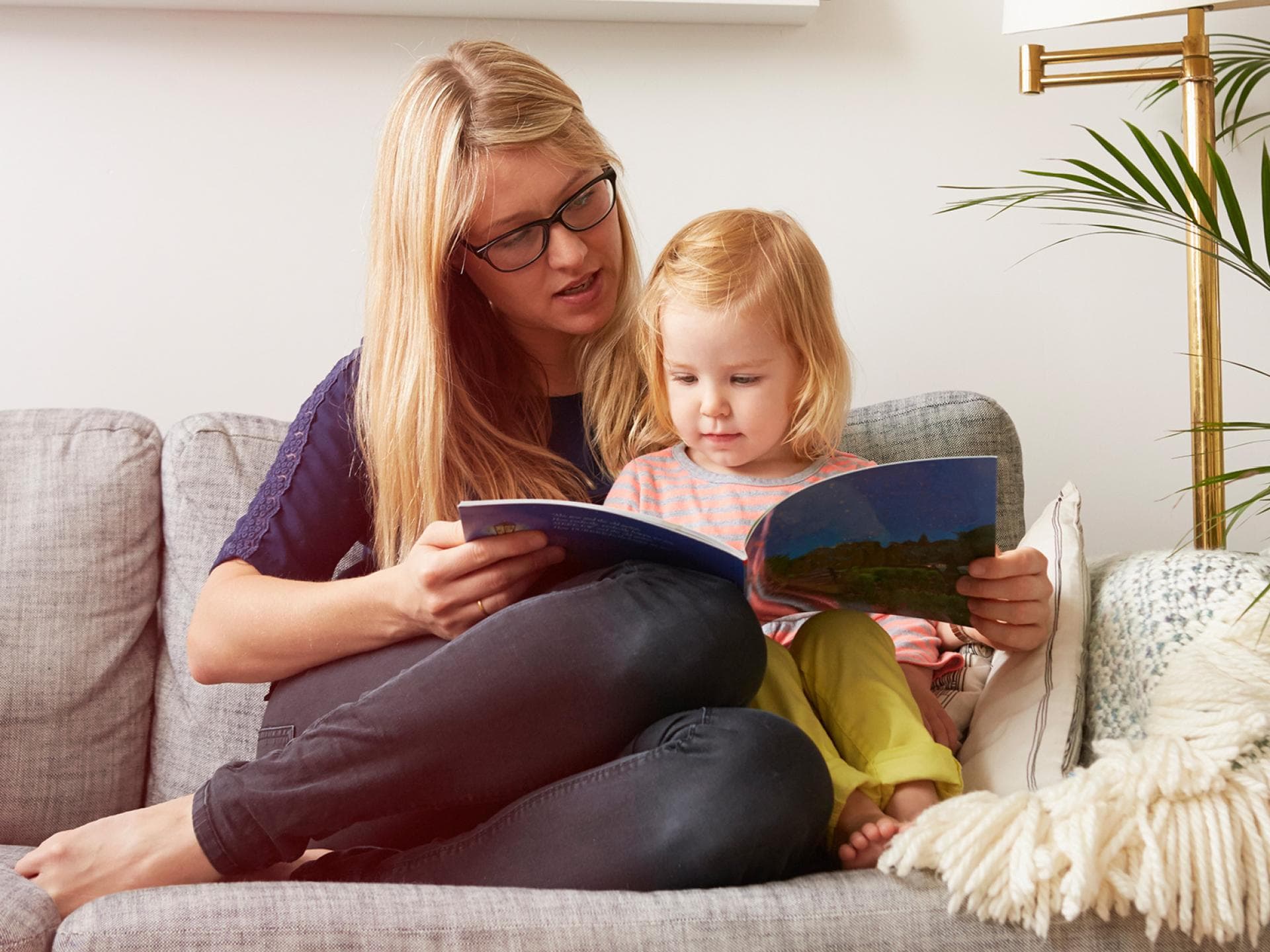 Bücher können Kindern dabei helfen, die Trennung der Eltern zu verarbeiten. Mutter liest mit Kind ein Buch.
