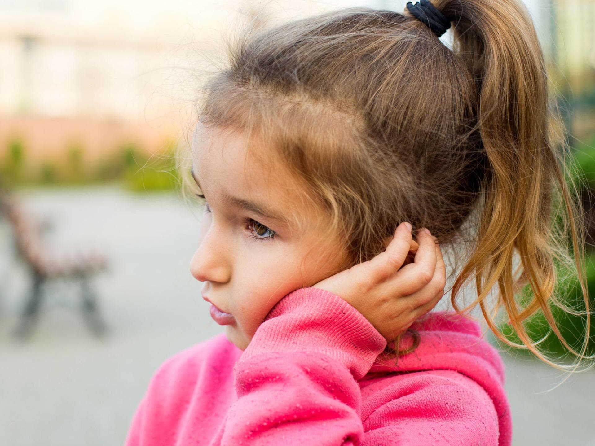 Bei Kindern führen vergrößerte Polypen mitunter zu Ohrenschmerzen oder anderen Beschwerden. Mädchen fasst sich ans Ohr.