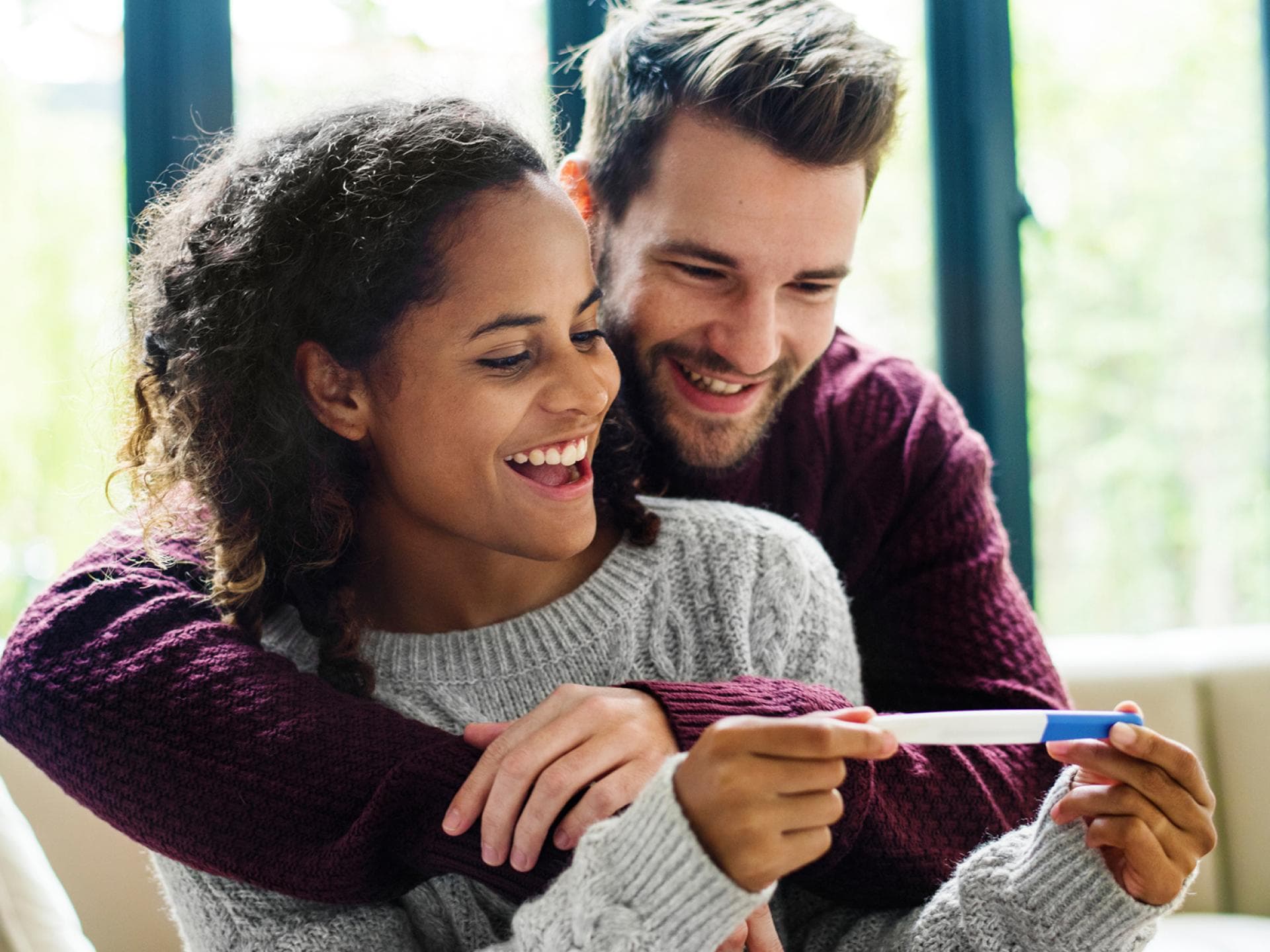 Auf eine verkündete Schwangerschaft folgen schnell Glückwünsche von Freunden und Familie. Paar freut sich über Schwangerschaftstest.