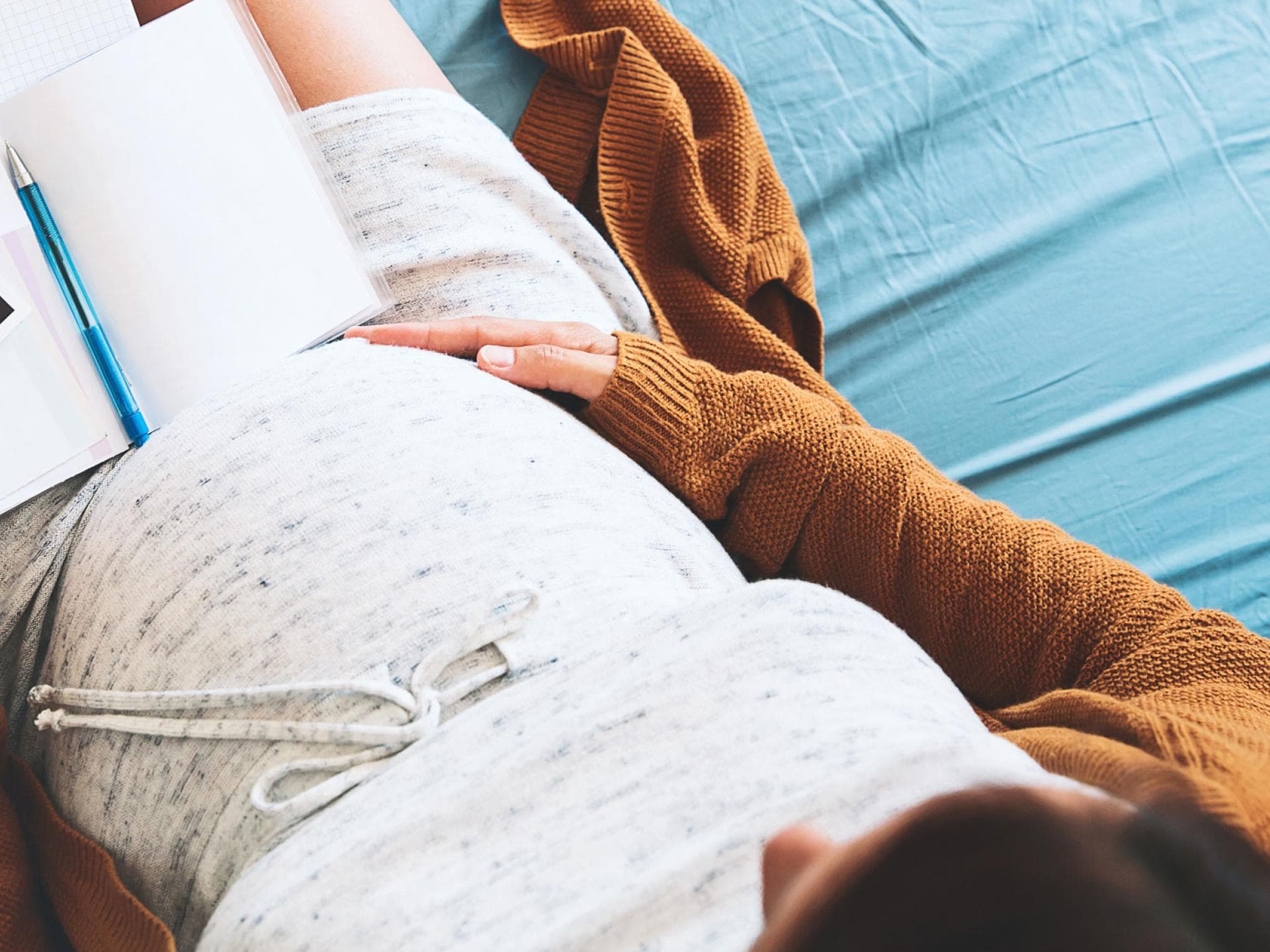 Der Mutterpass steckt voller – teils unverständlicher – Abkürzungen. Schwangere schaut sich Mutterpass und Ultraschallbild an.