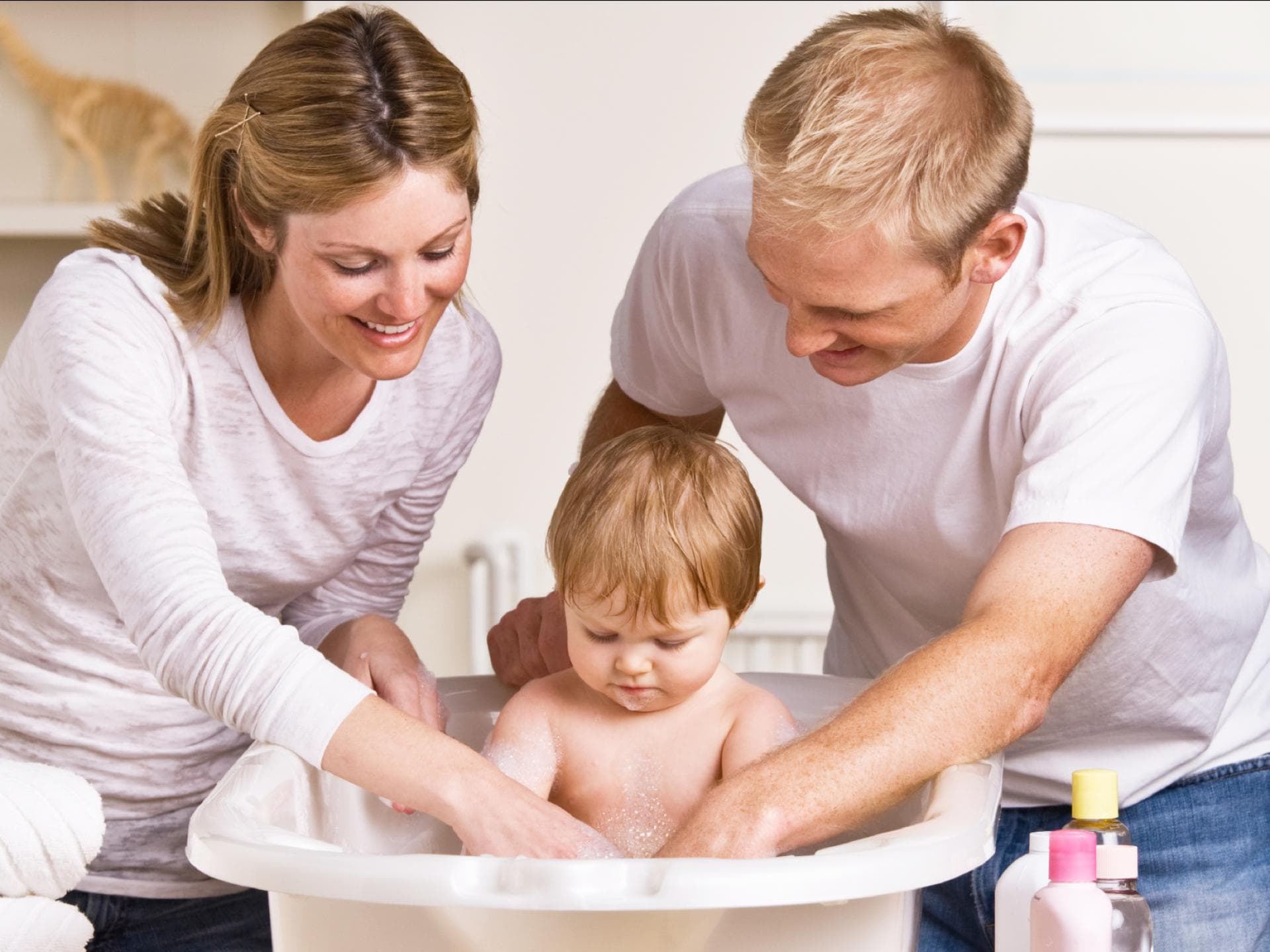 Mit Kindern ist immer viel zu tun, da ist eine Arbeitsteilung notwendig. Eltern baden ihr Kleinkind.